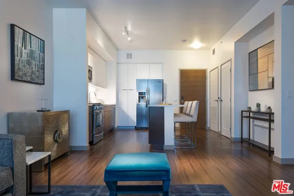 a living room with stainless steel appliances furniture and a wooden floor
