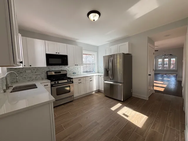 a kitchen with granite countertop a refrigerator a sink a stove a microwave and wooden floor