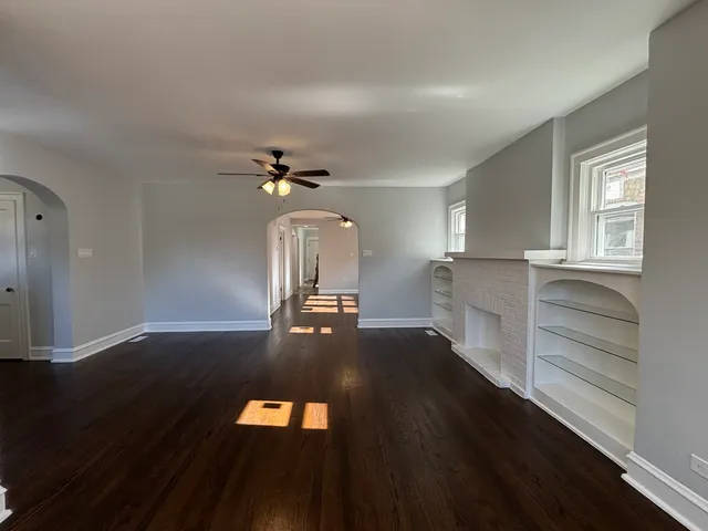 a view of a livingroom with wooden floor a ceiling fan and windows