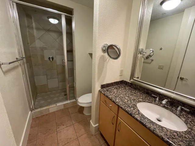 a bathroom with a granite countertop sink a mirror and a shower