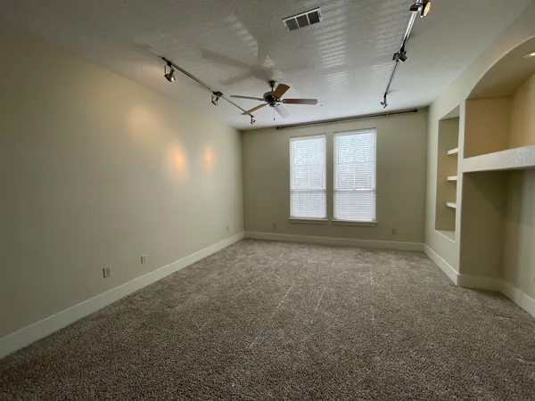 an empty room with windows and fan
