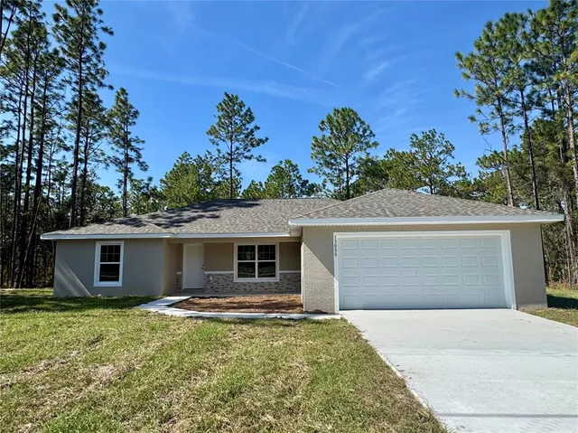 a front view of house with yard and trees in the background