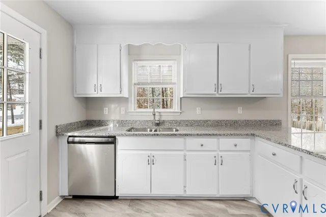 a kitchen with granite countertop white cabinets and a sink