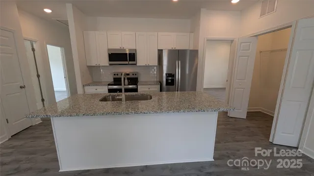 a kitchen with stainless steel appliances granite countertop a refrigerator and a sink
