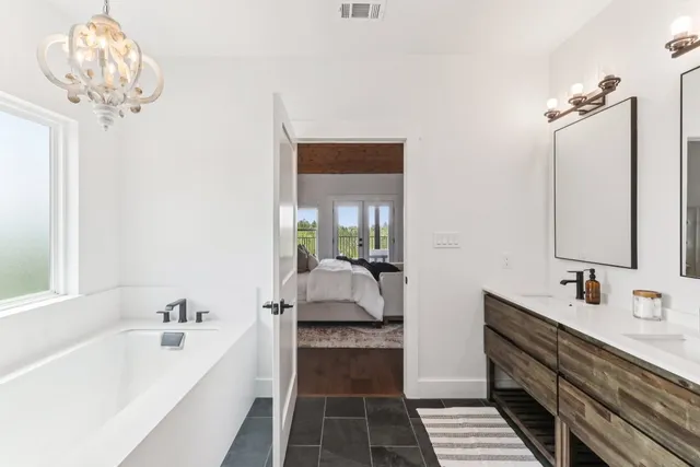 a bathroom with a double vanity sink a mirror and a bathtub