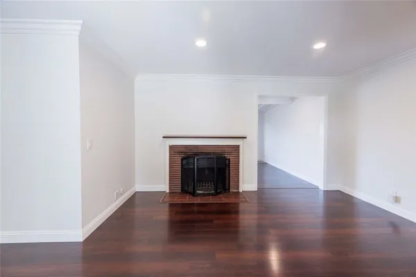 a view of an empty room with wooden floor fireplace and a window