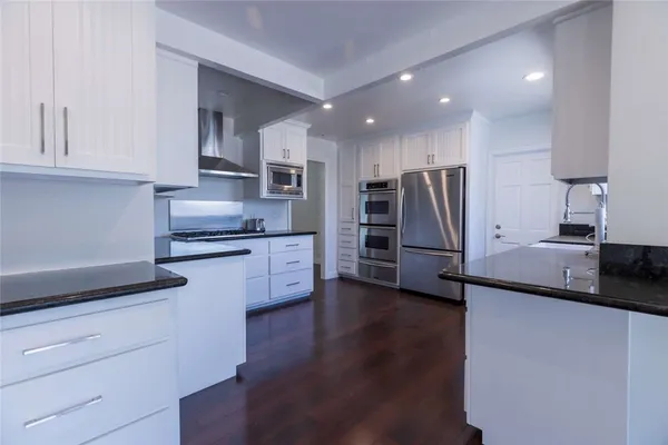 a kitchen with stainless steel appliances kitchen island granite countertop a refrigerator and a stove top oven