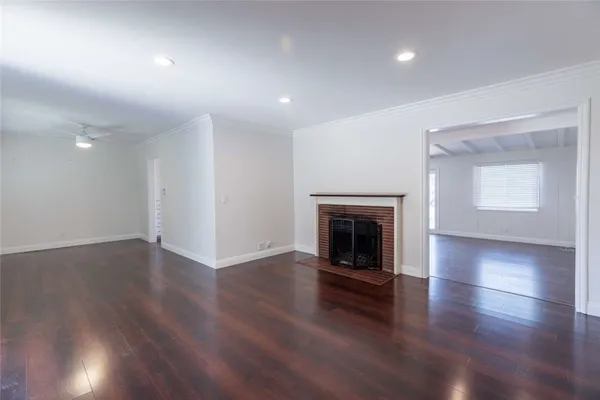 an empty room with wooden floor fireplace and windows