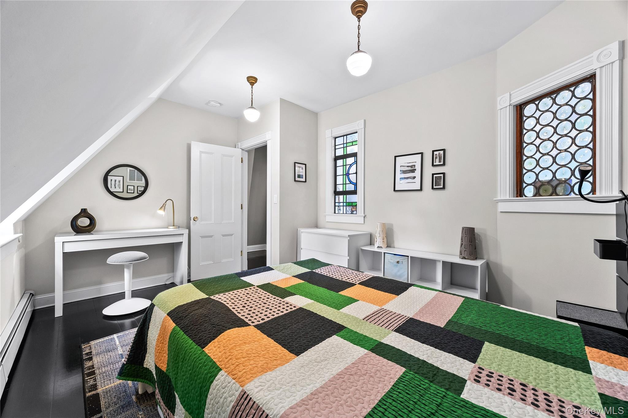 19 Howe Place Bronxville, NY 10708 - Photo 25 of 37 Bedroom featuring dark wood-finish flooring, two decorative stained-glass windows, sloped ceiling detail, and built-in shelving