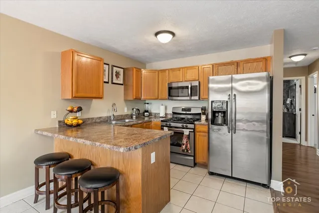 a kitchen with stainless steel appliances granite countertop a refrigerator a stove a sink a dining table and chairs