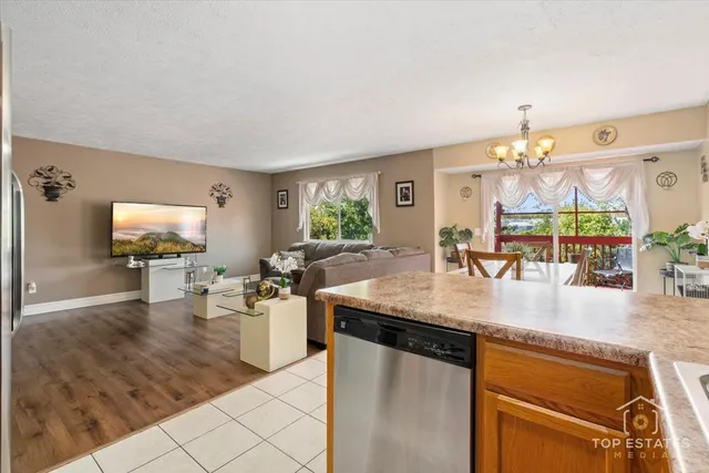 a kitchen with stainless steel appliances granite countertop a sink dishwasher and a flat screen tv