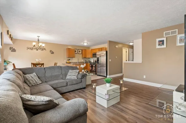a living room with furniture kitchen view and a chandelier