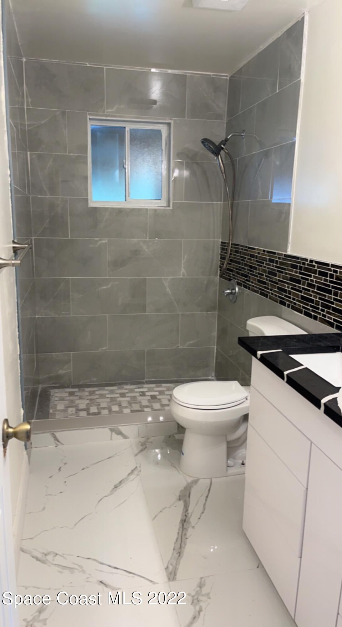 219 Eldron Boulevard Southeast Palm Bay, FL 32909 - Photo 3 of 9 a bathroom with a toilet a sink and shower