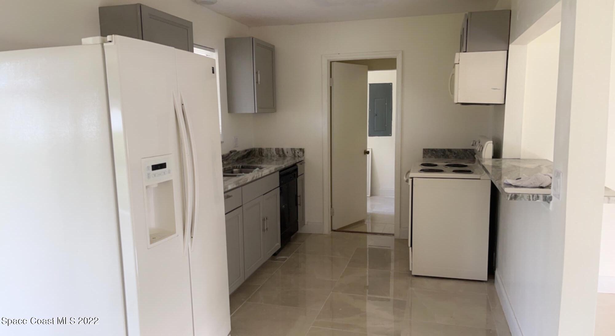 219 Eldron Boulevard Southeast Palm Bay, FL 32909 - Photo 6 of 9 a kitchen with a refrigerator sink stove and cabinets