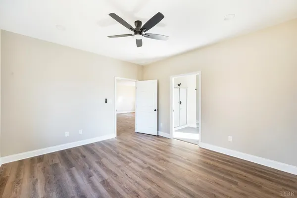 a large white kitchen with granite countertop a refrigerator a sink dishwasher and white cabinets with wooden floor