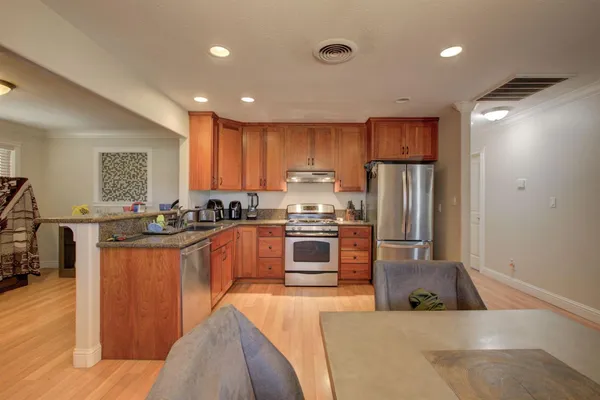 a large kitchen with kitchen island a large counter top space a sink stainless steel appliances and cabinets