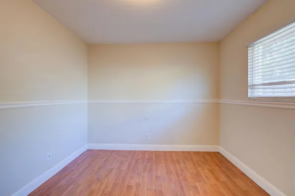a view of an empty room with wooden floor and a window