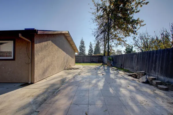 a backyard of a house with table and chairs a barbeque with wooden fence