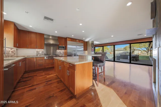 a large kitchen with stainless steel appliances granite countertop a large counter top a stove a sink and a refrigerator