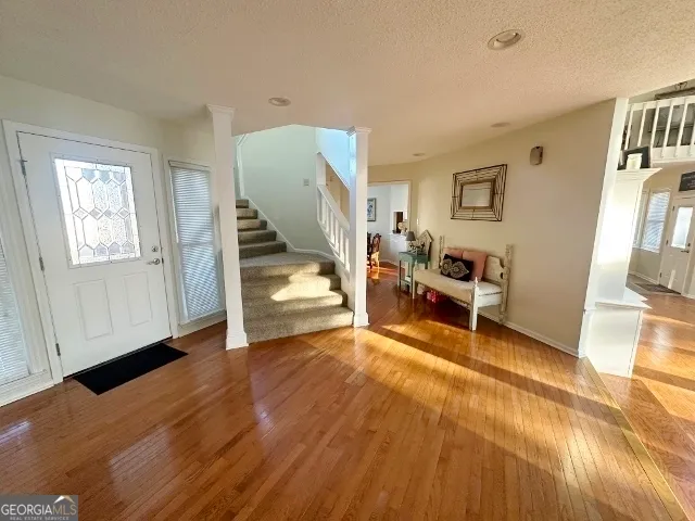 a view of an empty room with wooden floor and stairs