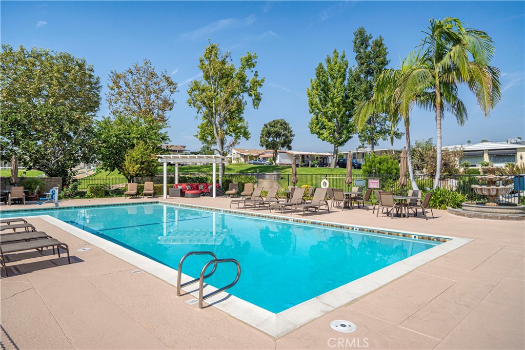 1001 West Lambert Road, Unit 153 La Habra, CA 90631 - Photo 22 of 24 a view of a swimming pool with a lawn chairs under palm trees
