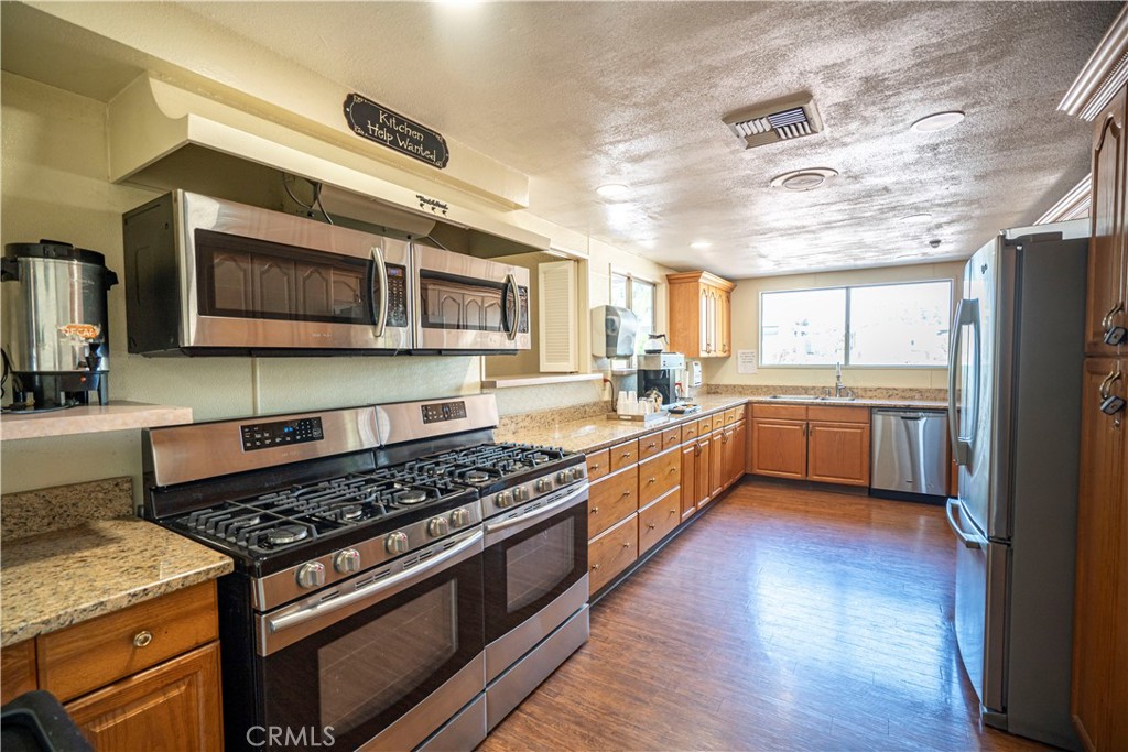 1001 West Lambert Road, Unit 153 La Habra, CA 90631 - Photo 27 of 28 a kitchen with stainless steel appliances kitchen island granite countertop a stove cabinets and a wooden floor