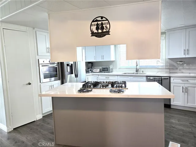 a kitchen with kitchen island granite countertop a sink a stove a refrigerator and cabinets