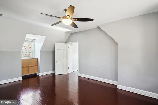 a view of an empty room with wooden floor and a ceiling fan