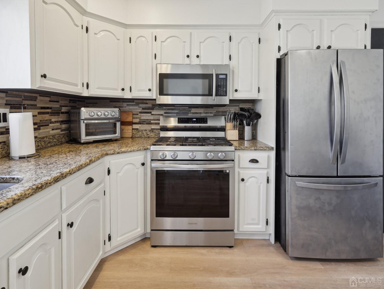 82 Normandy Road Colonia, NJ 07067 - Photo 12 of 33 a kitchen with granite countertop white cabinets and stainless steel appliances