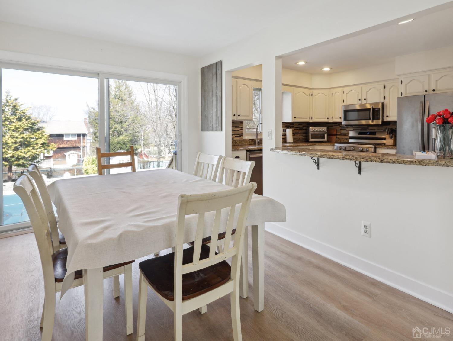82 Normandy Road Colonia, NJ 07067 - Photo 7 of 33 a kitchen with stainless steel appliances kitchen island granite countertop a stove a refrigerator a dining table and chairs with wooden floor