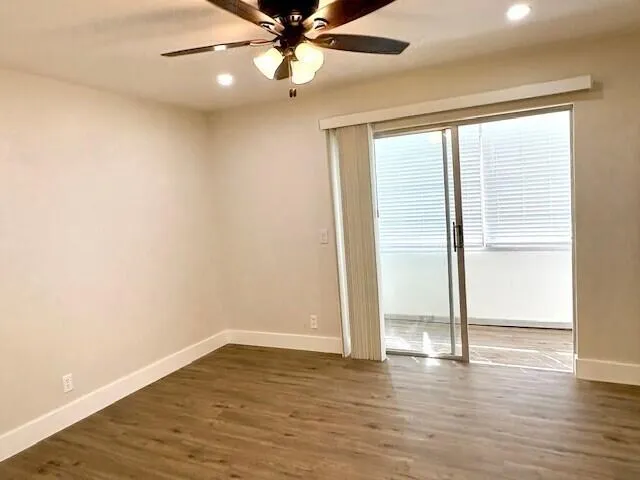 an empty room with wooden floor fan and windows