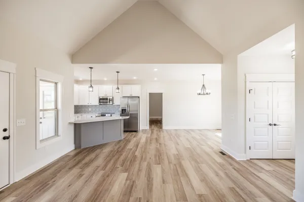 an empty room with wooden floor chandelier and windows