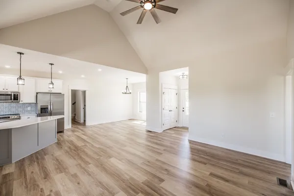 an empty room with wooden floor closet and windows