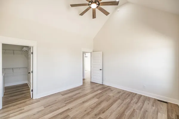 an empty room with wooden floor fan and windows