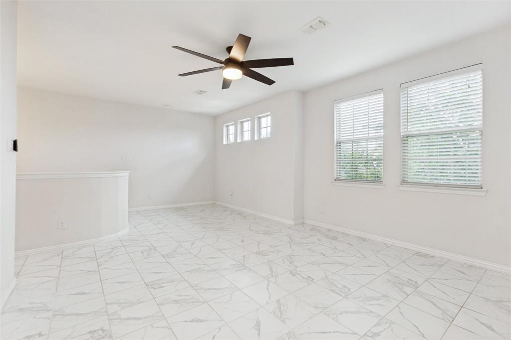 605 Ansley Way Allen, TX 75013 - Photo 16 of 28 Spacious room featuring large format white tile flooring, a dark-toned ceiling fan with integrated lighting, and multiple windows with blinds providing natural illumination