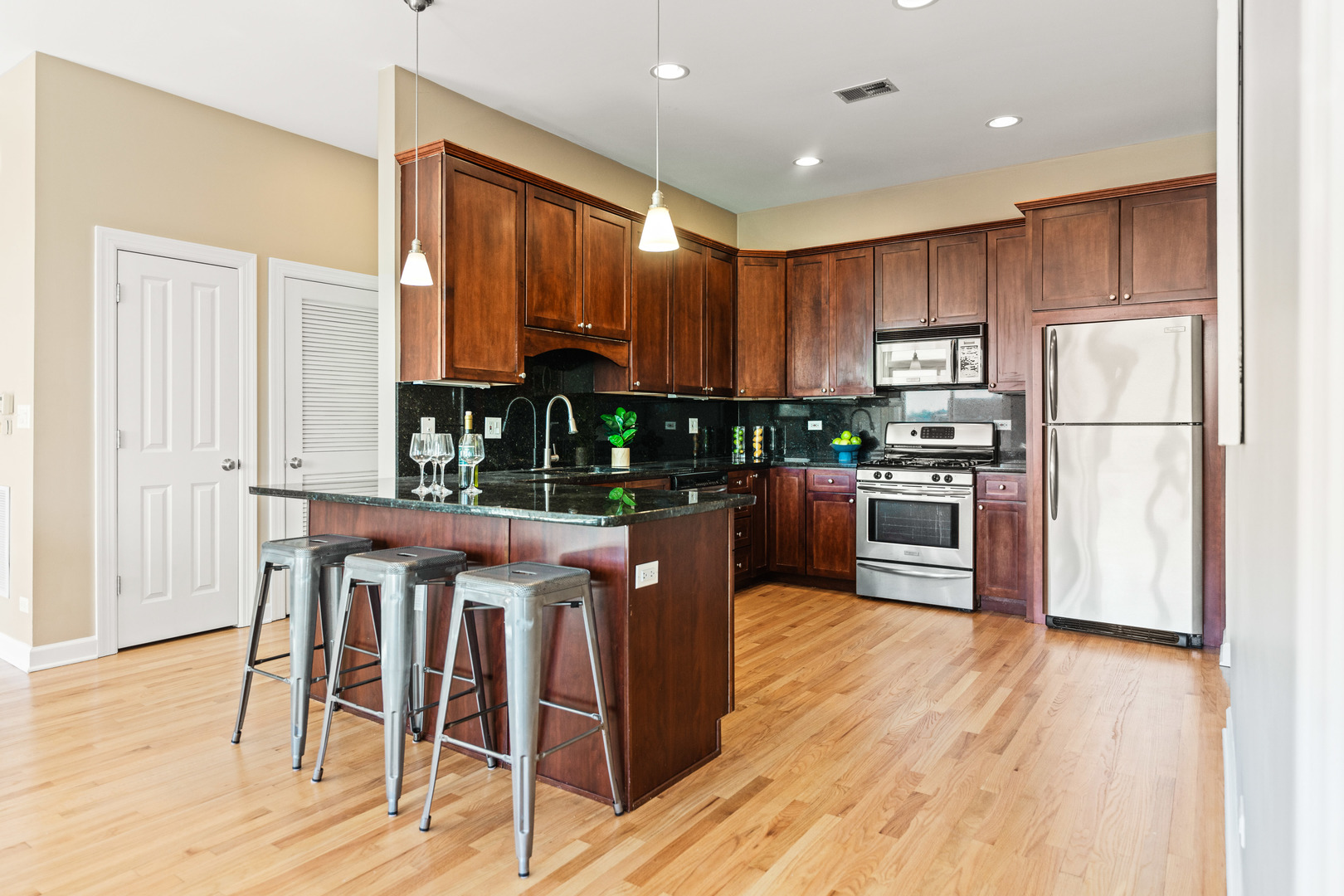 4603 North Racine Avenue, Unit 403 Chicago, IL 60640 - Photo 6 of 21 a kitchen with stainless steel appliances wooden floors and wooden cabinets