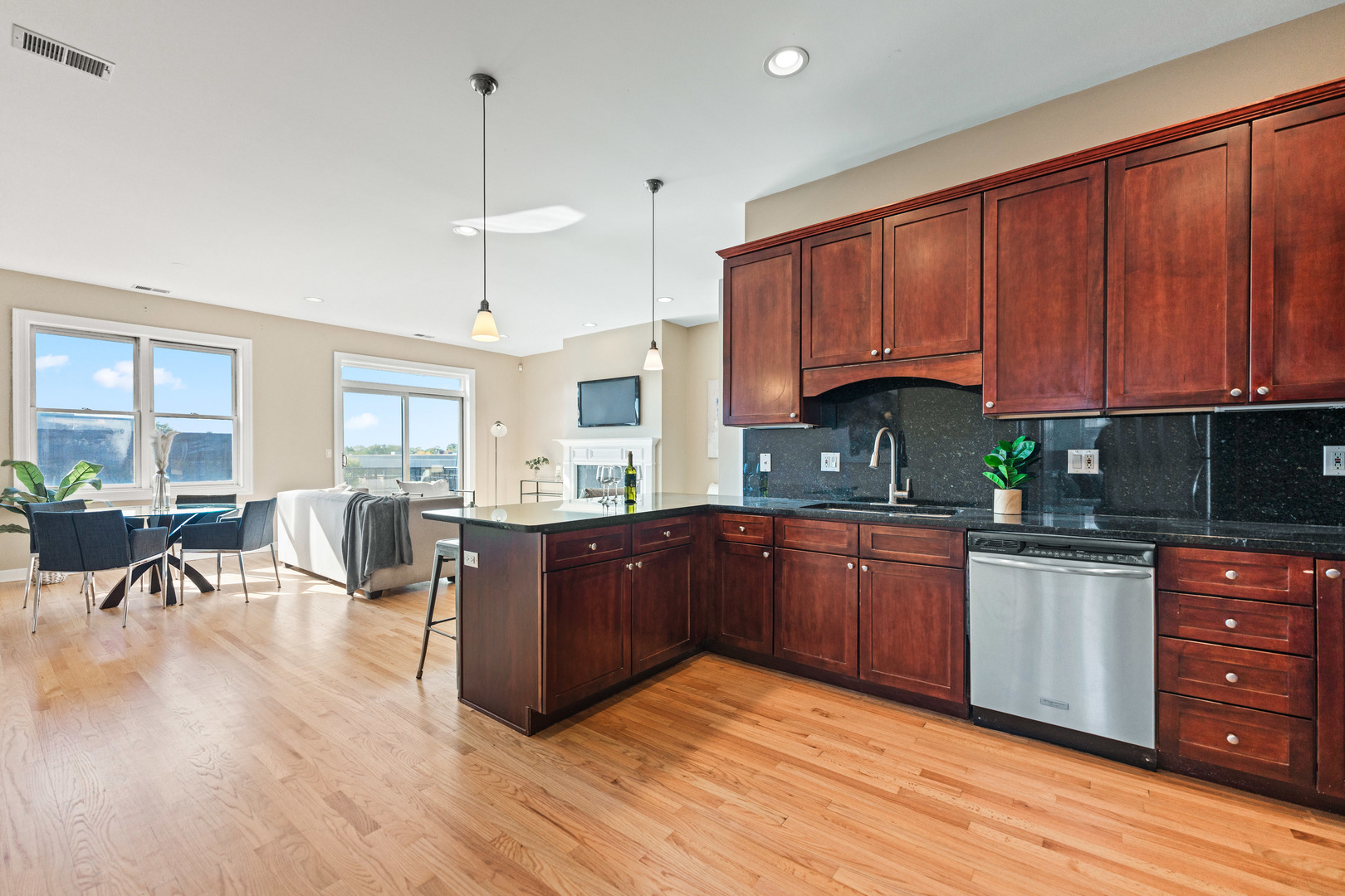 4603 North Racine Avenue, Unit 403 Chicago, IL 60640 - Photo 8 of 21 a kitchen with stainless steel appliances granite countertop wooden cabinets a refrigerator a sink a stove a dining table and chairs with wooden floor