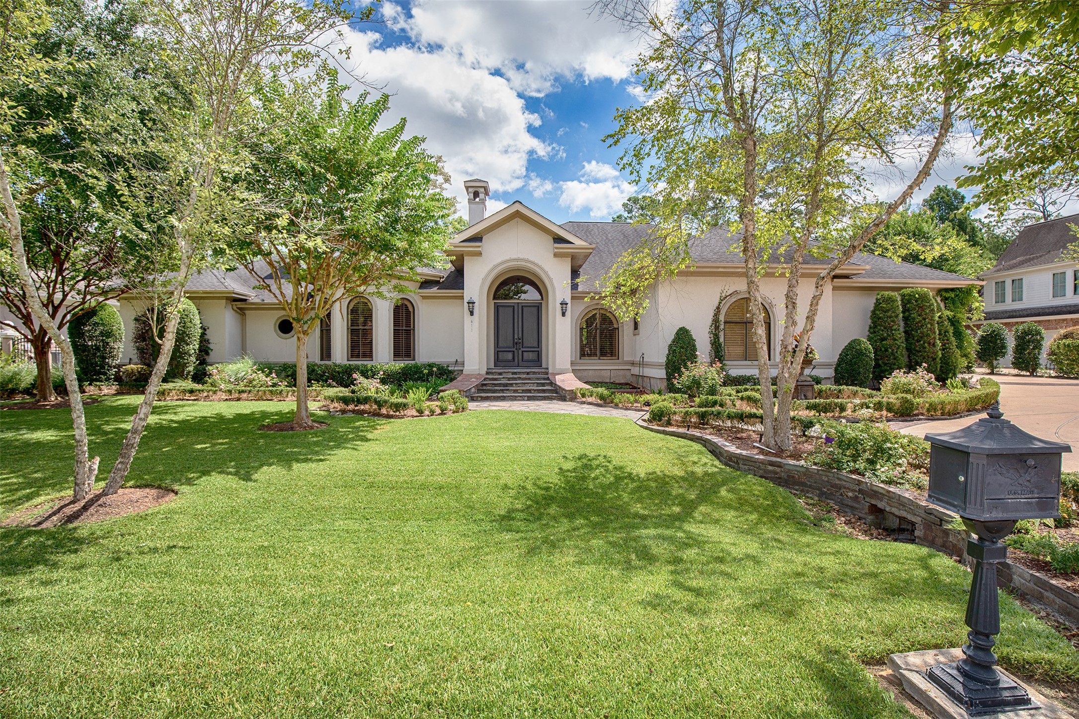 a front view of a house with garden and trees