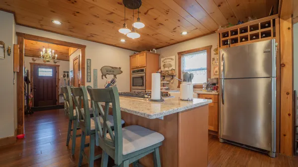 a kitchen with stainless steel appliances granite countertop a refrigerator a microwave oven a dining table and chairs with wooden floor