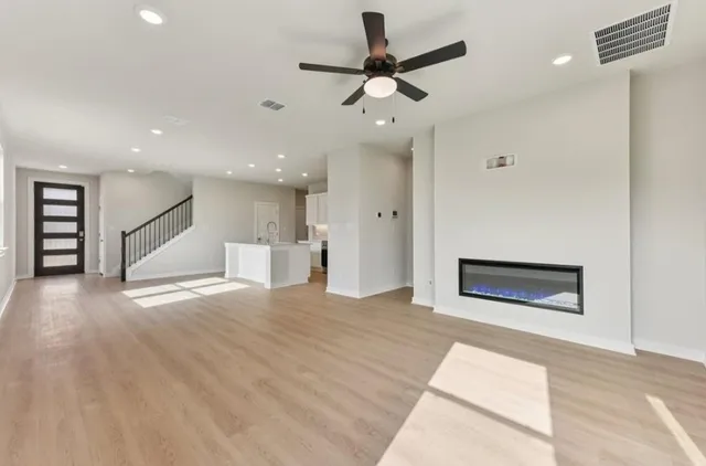 a view of an empty room with a window and a kitchen