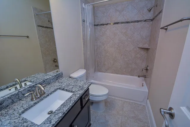 an empty room with chandelier fan and windows