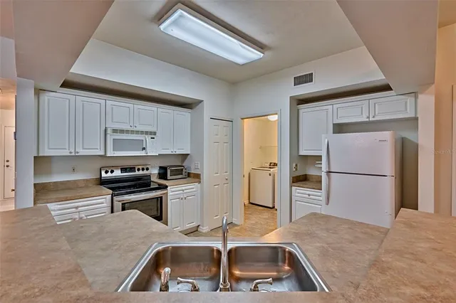 a kitchen with a sink a refrigerator and cabinets