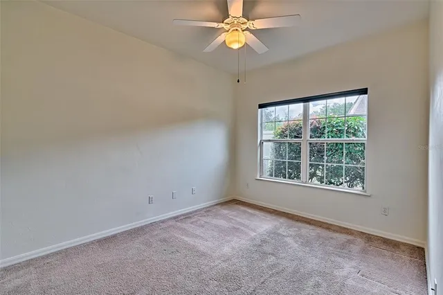 an empty room with a window and a fan