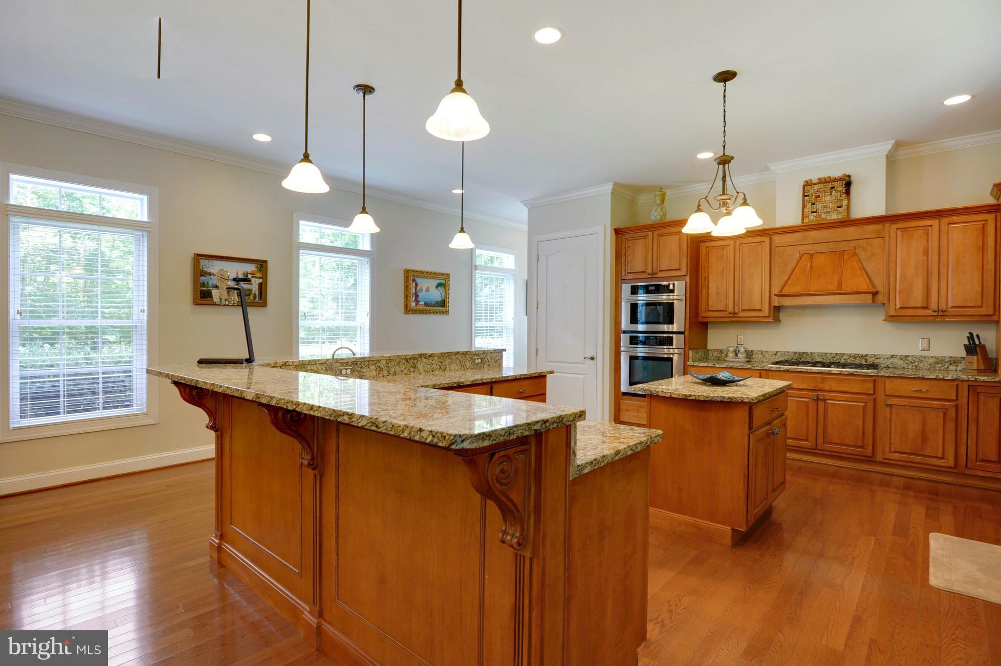 9440 Billingsley Road White Plains, MD 20695 - Photo 5 of 30 a kitchen with granite countertop a stove a sink a center island and wooden floor