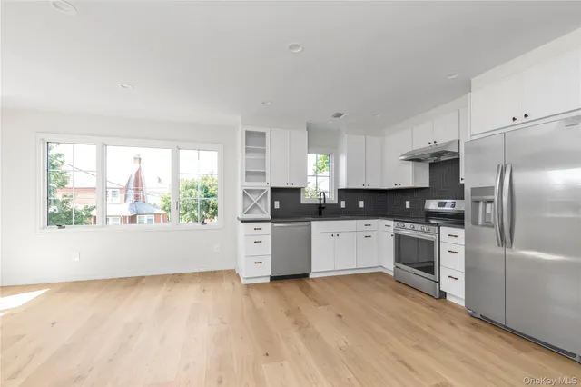 a kitchen with a refrigerator a stove top oven a sink and a window