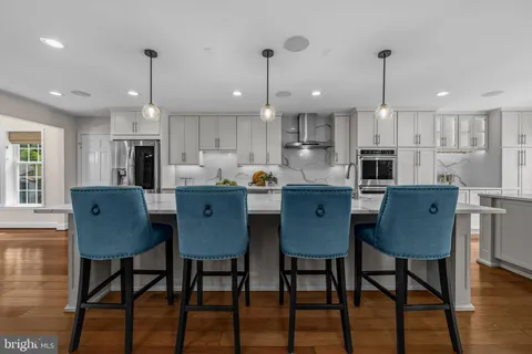 a dining room with stainless steel appliances kitchen island granite countertop a dining table chairs and a refrigerator