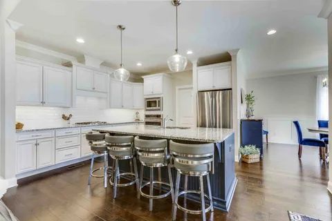 a kitchen with stainless steel appliances granite countertop a stove a sink and white cabinets