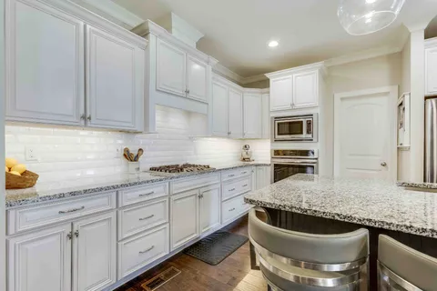 a kitchen with stainless steel appliances kitchen island granite countertop a sink a stove a dining table and chairs