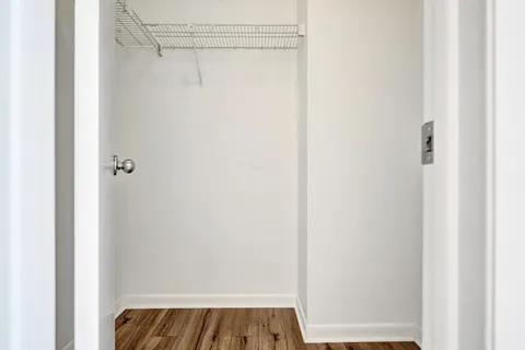 a view of an empty room with wooden floor and a floor to ceiling window