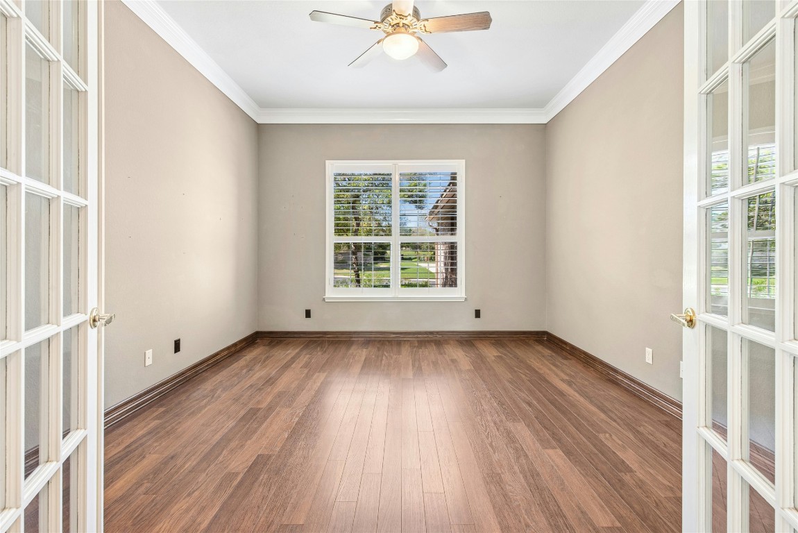 316 Trail Of The Flowers Georgetown, TX 78633 - Photo 18 of 40 an empty room with wooden floor chandelier fan and windows